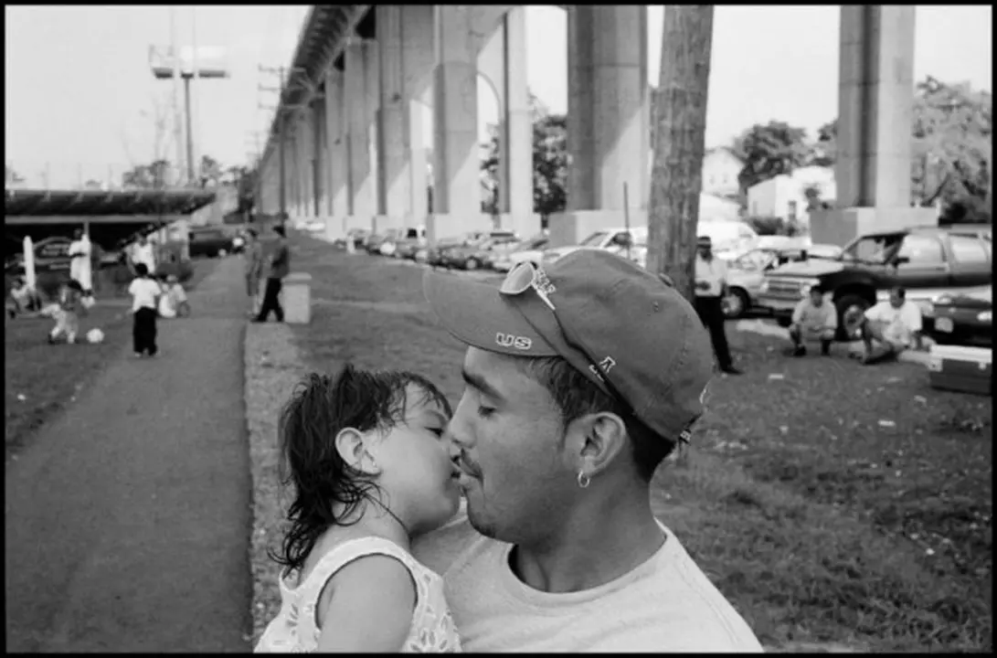 USA. Perth Amboy, New Jersey. 2000. During a Continental Soccer League game at Rudyk Park, Marco Meneses kisses his daughter, Melanie, who is 1 year and 8 months old. Games happen every weekend at the park.