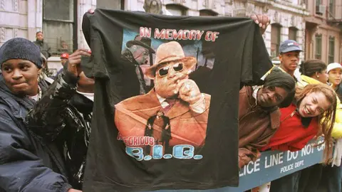 BROOKLYN, :  A man displays a T-shirt tribute to rapper Biggie Smalls aka The Notorious B.I.G 18 March as friends and fans lined the funeral procession route through his old neighborhood in Brooklyn. "Biggie" 24, who's real name was Christopher Wallace, died 09 March in a drive-by shooting in Los Angeles. AFP PHOTO  Jon LEVY (Photo credit should read JON LEVY/AFP/Getty Images)