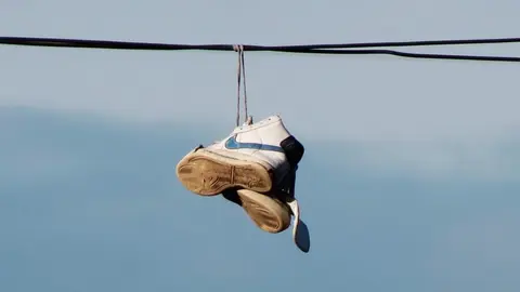 Zapatillas colgadas de los cables el&eacute;ctricos en las calles